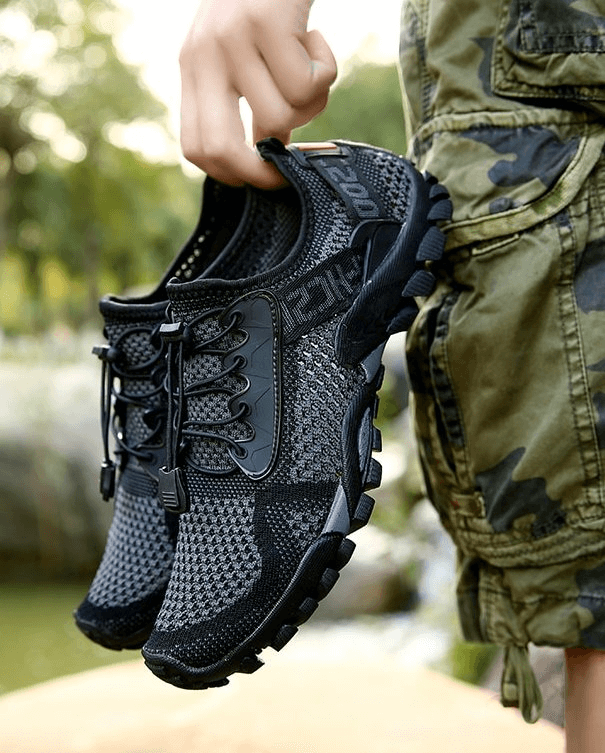 Man holding breathable elastic camping shoes, perfect for outdoor activities, featuring mesh upper and durable rubber outsole.